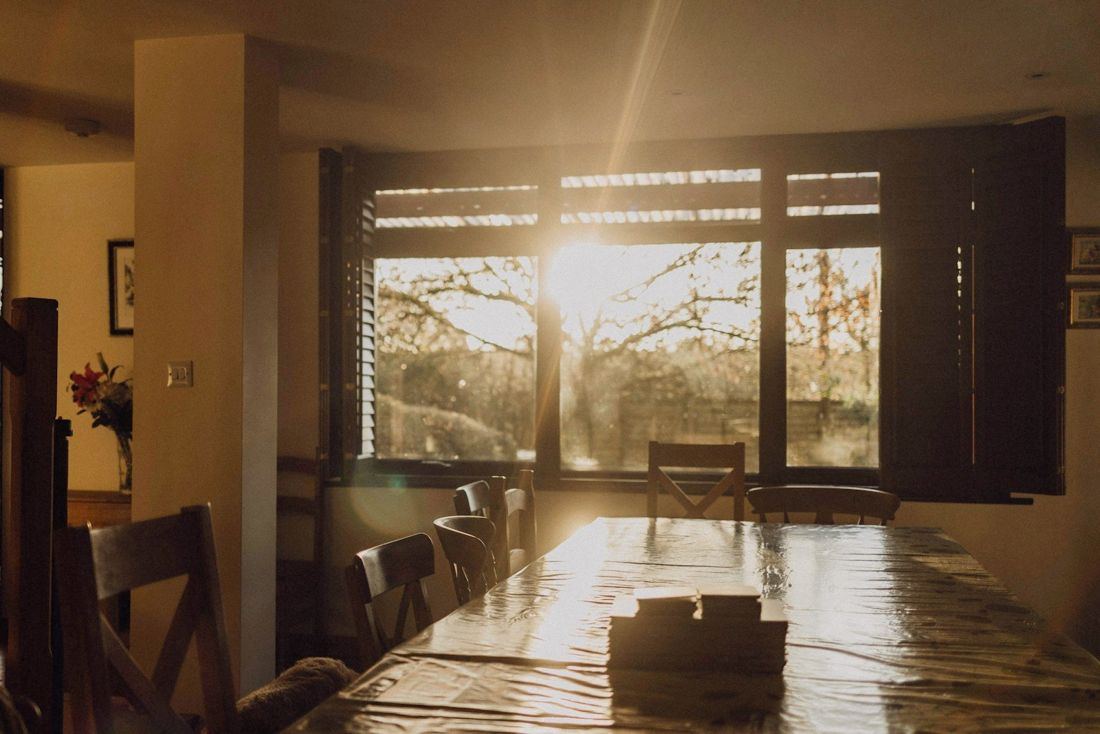 Una persona junto a una ventana al anochecer, con la casa a oscuras